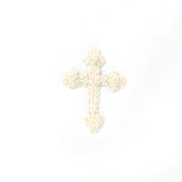 Cross-shaped object made of white and ivory embroidery thread on a white background