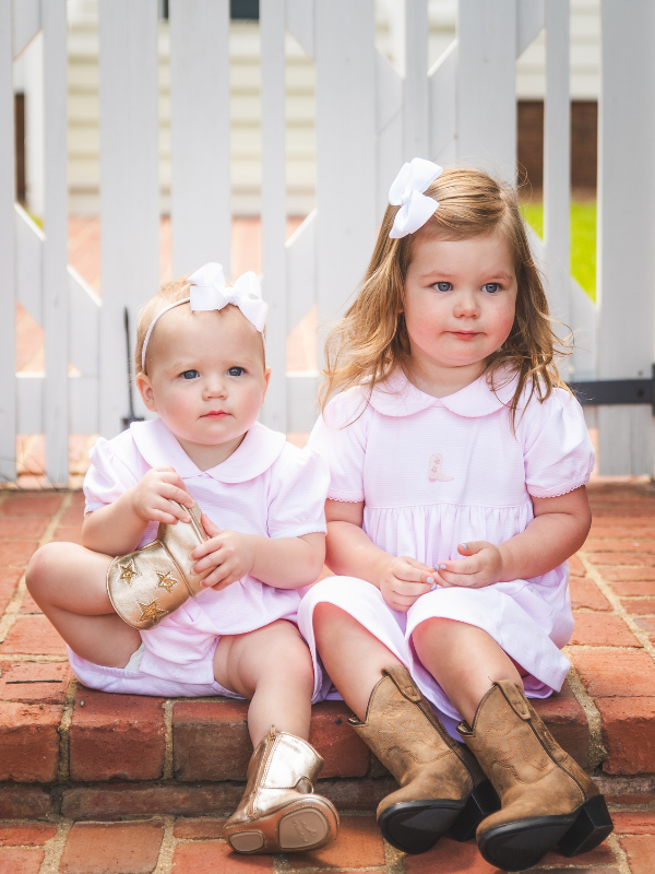 Lifestyle photo – little girl wearing the Pink Mini Stripe Cowboy Boot Dress and Baby Bubbleby Milly Marie Pima.