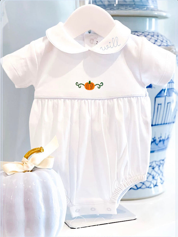 White baby romper with pumpkin design on a mannequin against a light background