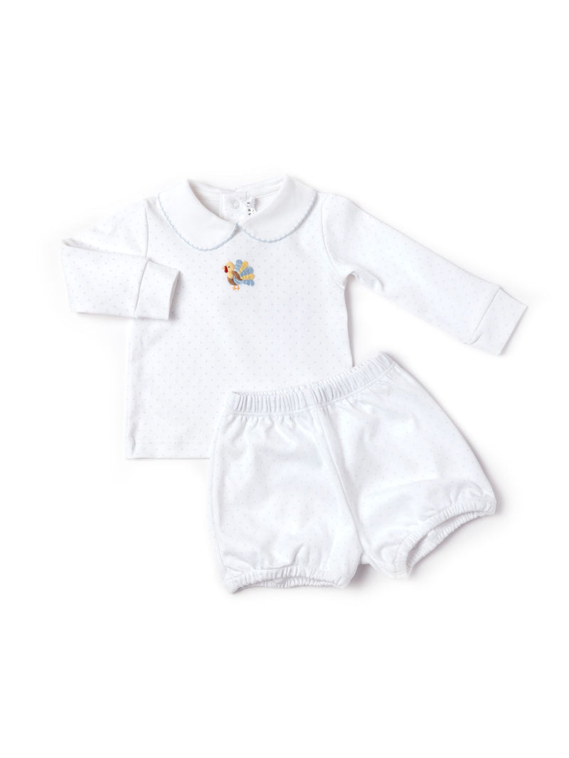 A two-piece baby boy outfit with a long-sleeved white top featuring a blue embroidered turkey and blue bitty dot pattern, and matching white bloomers.