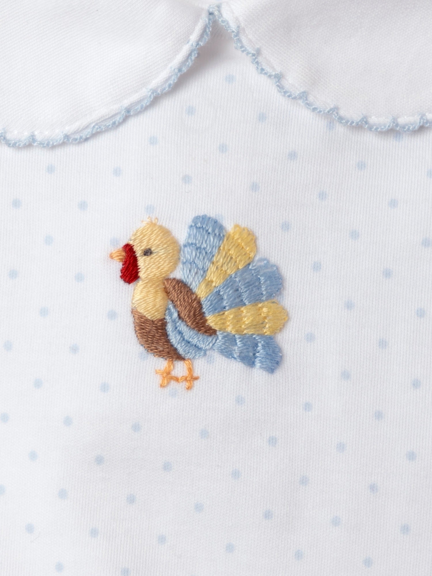 Embroidered turkey design on a white fabric with blue polka dots