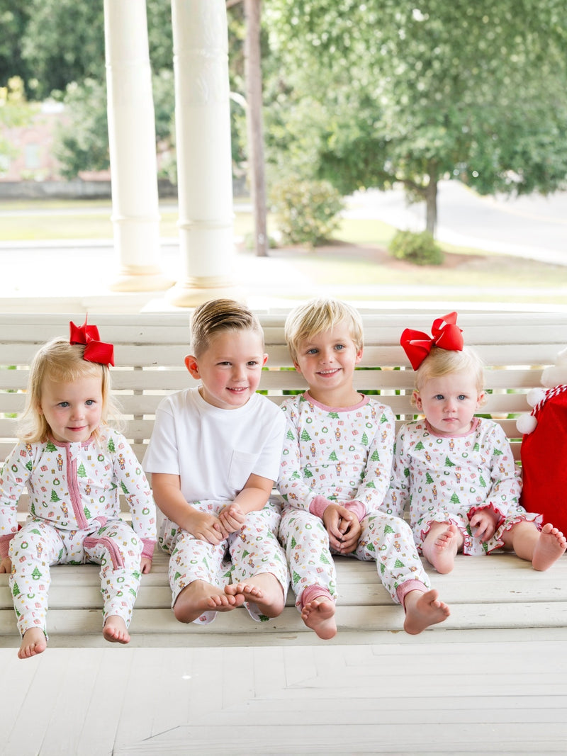 Four children in matching pajamas sitting on a porch.