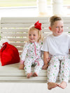 Two children in matching pajamas sitting on a white bench.