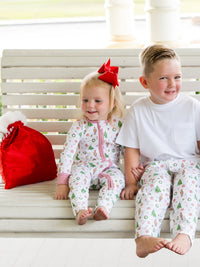 Two children in matching pajamas sitting on a white bench.