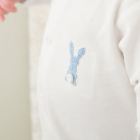 Embroidered blue bunny design on a white fabric background