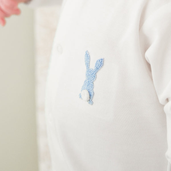 Embroidered blue bunny design on a white fabric background