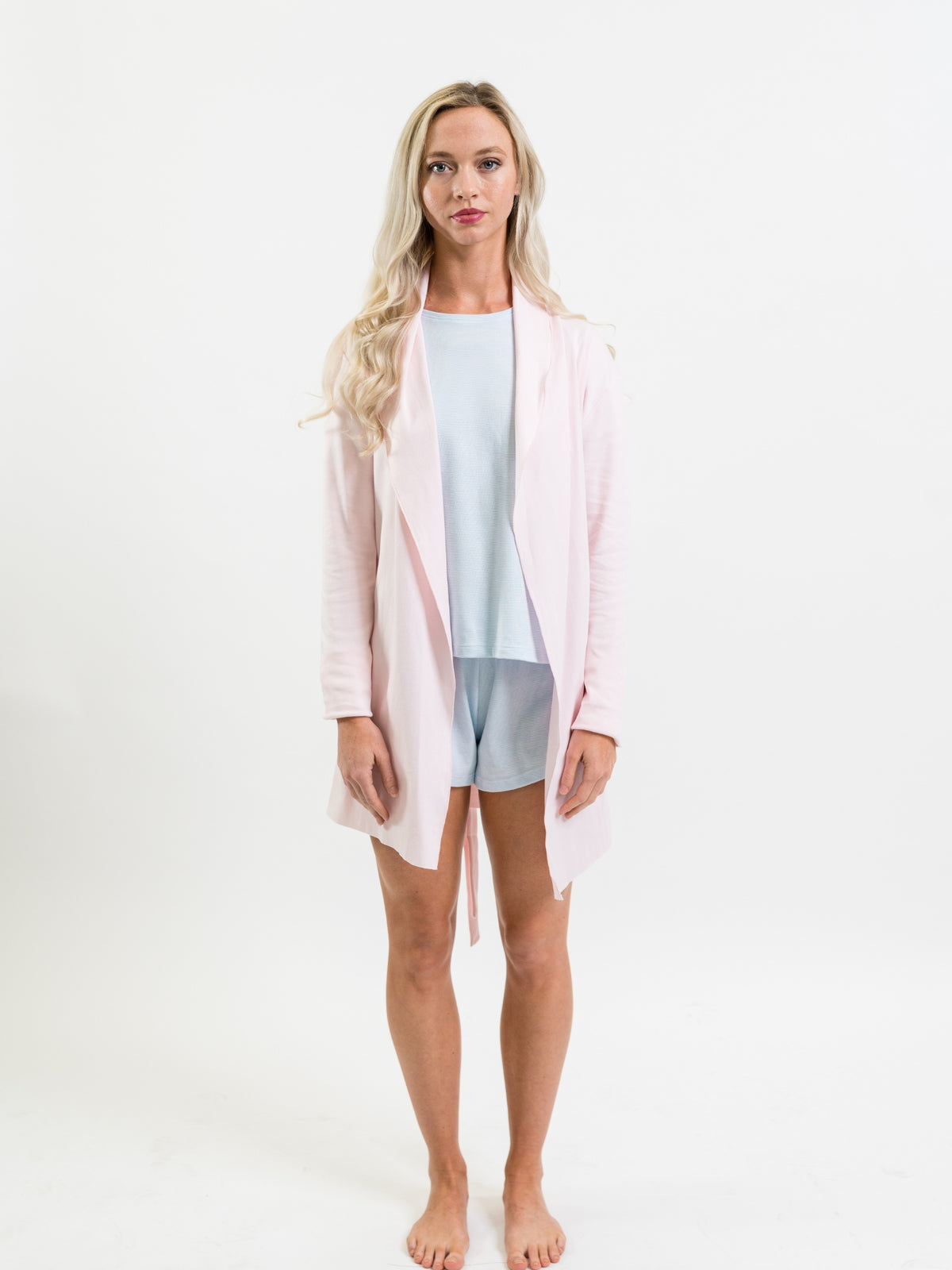 Woman wearing a light pink robe over a light blue lounge set on a white background