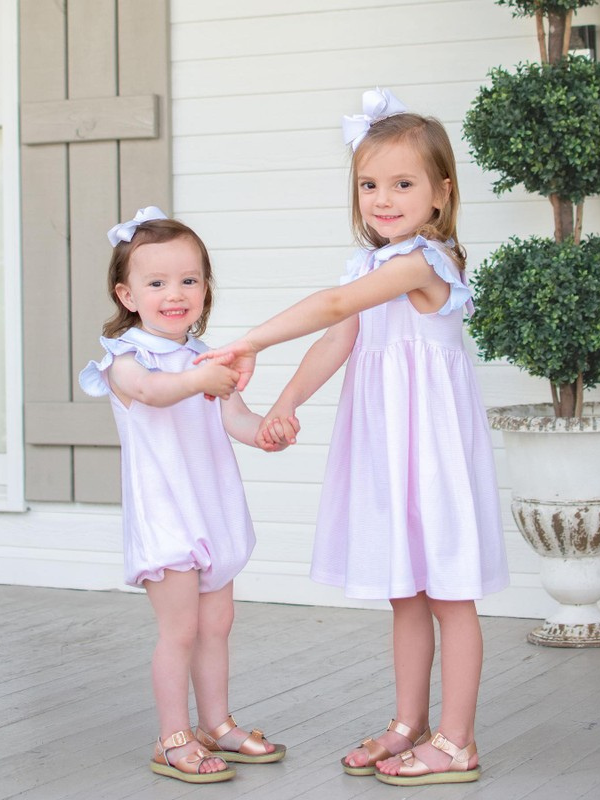 sisters holding hands.  little sister in pima cotton baby bubble outfit and big sister in a matching pima cotton dress