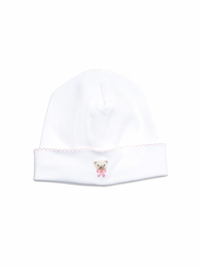 A white Pima cotton baby hat with light pink picot trim and a teddy bear face embroidered in the middle.